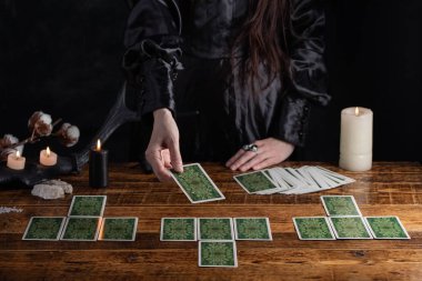 Female tells the future with playing cards. Tarot card concept on the table. Prediction of the future. Fortuneteller hands in black vestments.Psychic.