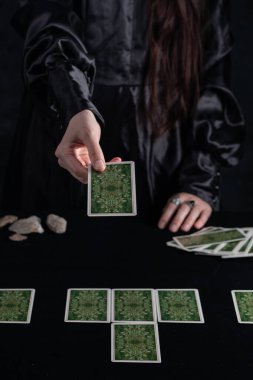 Female tells the future with playing cards. Tarot card concept on the table. Prediction of the future. Fortuneteller hands in black vestments.Psychic.