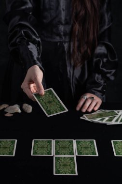 Female tells the future with playing cards. Tarot card concept on the table. Prediction of the future. Fortuneteller hands in black vestments.Psychic.
