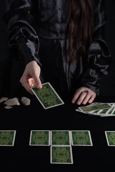 Female tells the future with playing cards. Tarot card concept on the table. Prediction of the future. Fortuneteller hands in black vestments.Psychic.