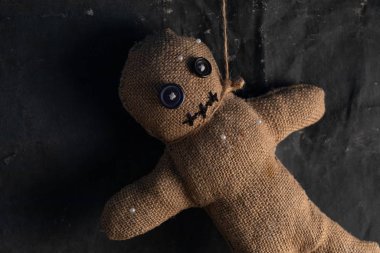 Voodoo doll on a black background with dramatic lighting. The concept of witchcraft and black art and the occult. Burlap doll.