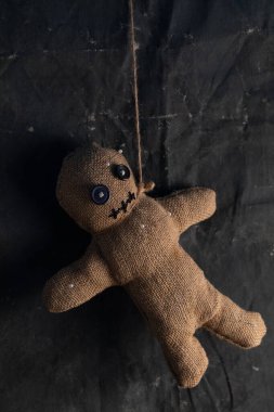 Voodoo doll on a black background with dramatic lighting. The concept of witchcraft and black art and the occult. Burlap doll.