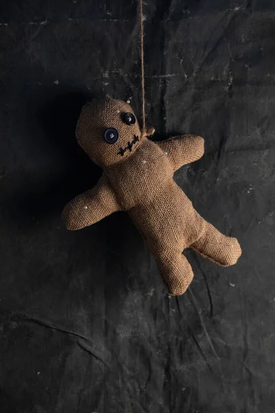 Voodoo doll on a black background with dramatic lighting. The concept of witchcraft and black art and the occult. Burlap doll.