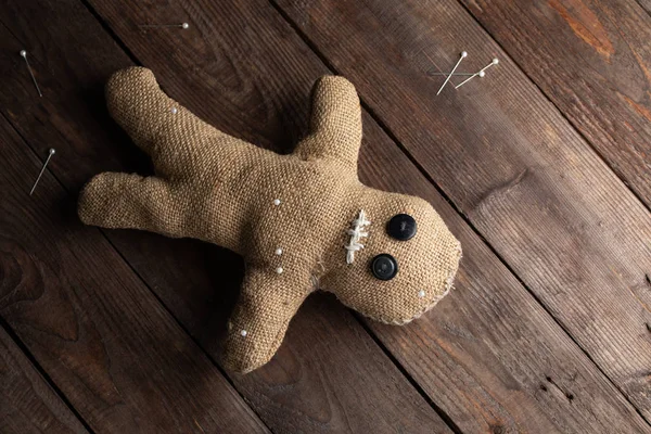 Voodoo doll on a wooden background with dramatic lighting. The concept of witchcraft and black art. Burlap doll on a wooden background. Pierce with maces. Copy space. — Stok fotoğraf