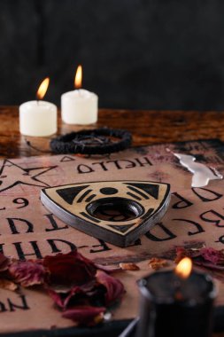 Spiritual board ouija with candles close-up. Mystical ritual of calling dead spirits. Macro. clipart
