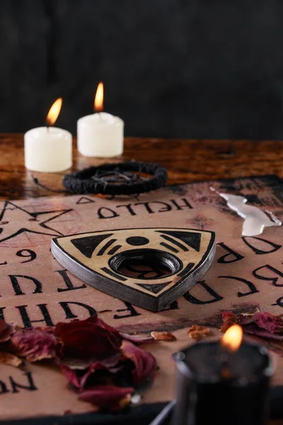 Andlig bräda ouija med ljus närbild. Mystisk ritual att kalla döda andar. Makro. — Stockfoto