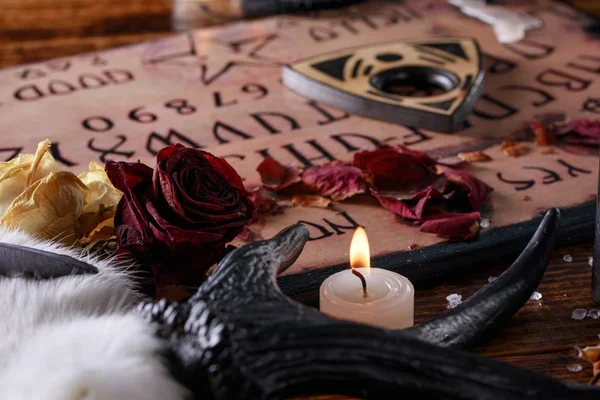 Tabla de diálogo y plancheta, también conocida como tabla Ouija, utilizada para comunicarse con los muertos y otros espíritus. La atmósfera del arte negro con velas y cuernos del animal . —  Fotos de Stock