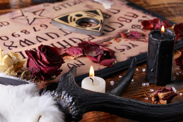 Talking board and planchette, also known as Ouija board, used for communicating with the dead and other spirits. The atmosphere of black art with candles and horns of the animal. — Stock Photo, Image