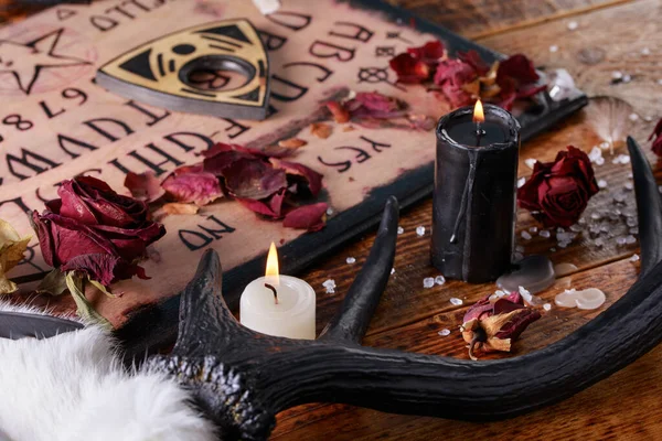 Tárgyalótábla és planchette, más néven Ouija tábla, használt kommunikálni a halott és más szellemek. A fekete művészet atmoszférája az állat gyertyáival és szarvaival. — Stock Fotó