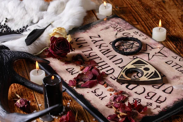 Talking board and planchette, also known as Ouija board, used for communicating with the dead and other spirits. The atmosphere of black art with candles and horns of the animal. — Stock Photo, Image