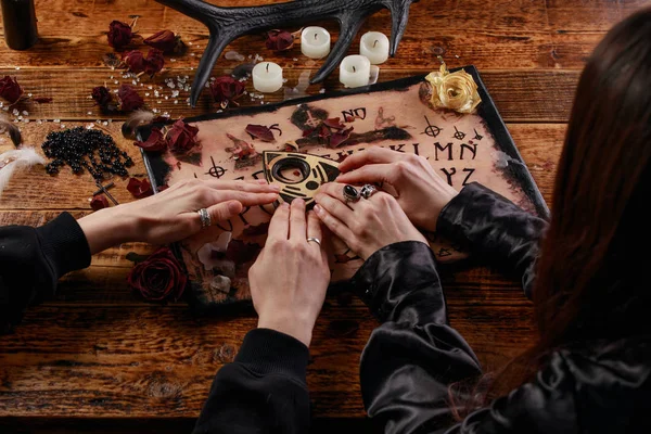 Människor som utför en seans med hjälp av en Ouija Board, eller Talking Spirit Board, med vita ljus. Skjuten från ovan. — Stockfoto