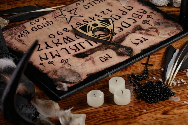 Ouija tábla gyertyákkal. Szeánsz a fa asztalon. A szellemek hívásának misztikus atmoszférája. Fekete mágia. — Stock Fotó