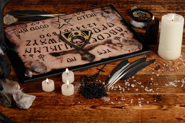 Ouija tábla gyertyákkal. Szeánsz a fa asztalon. A szellemek hívásának misztikus atmoszférája. Fekete mágia. — Stock Fotó