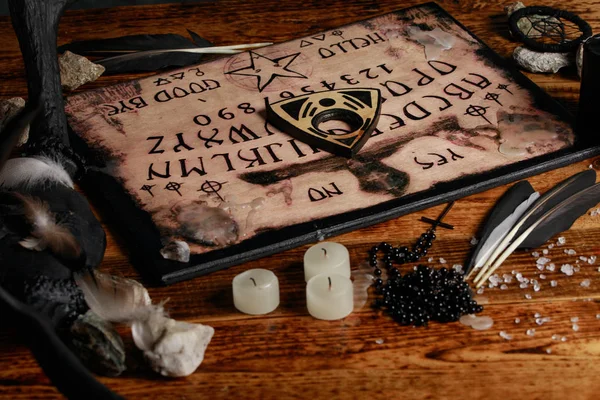 Ouija Board with candles. Seance on wooden table. The mystical atmosphere of the call of spirits. Black magic. — Stock Photo, Image