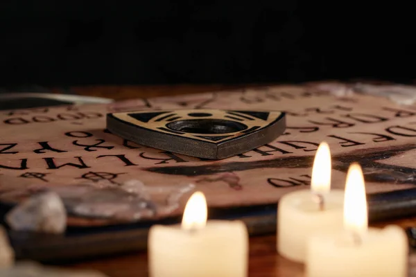 Spiritual board ouija with candles close-up. Mystical ritual of calling dead spirits. Macro. — Stock Photo, Image