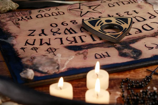 Tabuleiro Ouija com velas. Sente-se na mesa de madeira. A atmosfera mística do chamado dos espíritos. Magia negra . — Fotografia de Stock