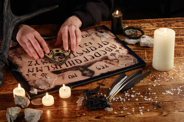 Hands on the devil's board. Session of calling spirits. Occult sciences, the atmosphere of black magic. — Stock Photo, Image