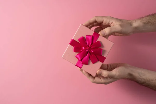 Валентинів день святкування концепції. Гарний подарунок від коханої. Коробка з луком у руках чоловіків на тонкому рожевому фоні. Копіюю простір. Плоть.. — стокове фото