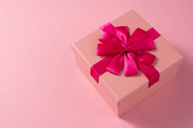 Sevgililer Günü kutlaması konsepti. Sevdiğin birinden güzel bir hediye. Hassas pembe arka planda fiyonklu bir kutu. Uzayı kopyala Düz yatıyordu. Yakın plan..