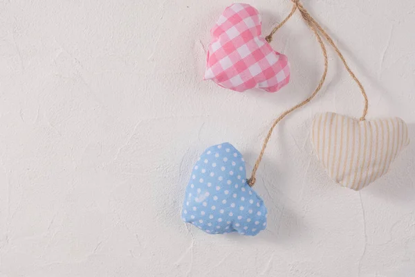 Hearts made of textile on a craft rope arranged together on a textured background. Valentine\'s day concept. Close-up.