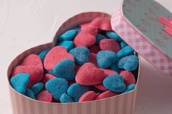 Sweet gift in a box in the form of a heart on a textural background. Marmalade in sugar blue and rose in the form of hearts Valentine\'s day holiday concept.