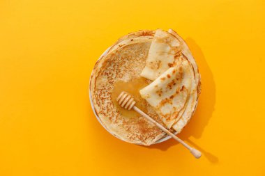 Sarı arka planda ballı nefis ev yapımı krepler. Üst manzara, yakın plan. Geleneksel tatil kutlaması konsepti. Rusça çeviri geniş ve mutlu Maslenitsa.