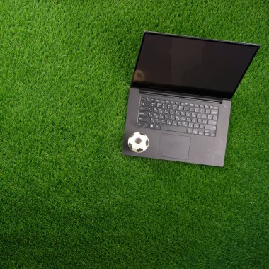 Yeşil çimlerde dizüstü bilgisayar ve futbol. Dünya Kupası konsepti. Boşluğu kopyala.