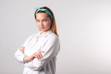 Kız gücü konsepti. Gri duvar arkasında izole edilmiş kendine güvenen genç bir kadın. Kadınsı ve bağımsız güç. Stüdyo çekimi.