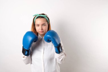 Kız gücü konsepti. Gri duvar arkasında izole edilmiş kendine güvenen genç bir kadın. Kadınsı ve bağımsız güç. Boks eldivenli kız. Kadın gücü konsepti. Bir kıza boks eldiveni giydirmek. Yakın plan..