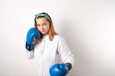 Kız gücü konsepti. Gri duvar arkasında izole edilmiş kendine güvenen genç bir kadın. Kadınsı ve bağımsız güç. Boks eldivenli kız. Kadın gücü konsepti. Bir kıza boks eldiveni giydirmek. Yakın plan..
