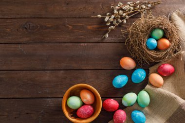 Ahşap bir arka planda bir sürü renkli paskalya yumurtası. Taşralı. Doğal kumaş ve bitkilerden dekorasyon. Paskalya kutlaması. Uzayı kopyala Düz yatıyordu