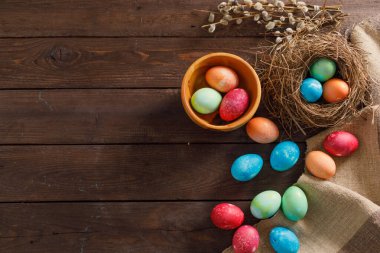 Ahşap bir arka planda bir sürü renkli paskalya yumurtası. Taşralı. Doğal kumaş ve bitkilerden dekorasyon. Paskalya kutlaması. Uzayı kopyala Düz yatıyordu