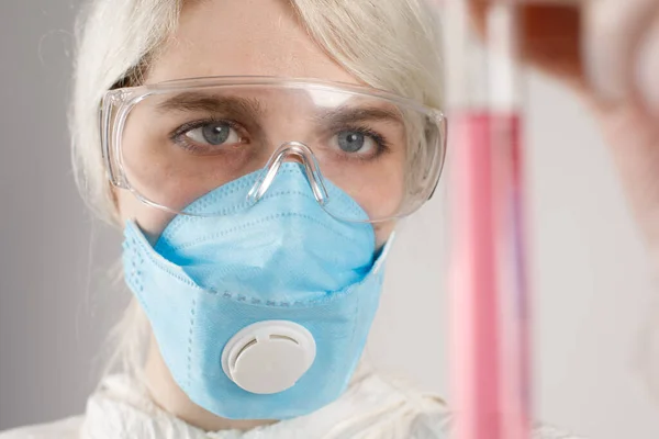 A girl in a protective suit and a respirator to protect health from viral, epidemic and infectious diseases. New Covid-19. Vaccine search concept. Stop the virus.