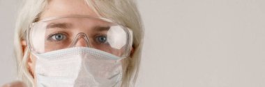 Sağlığı viral, salgın ve bulaşıcı hastalıklardan korumak için koruyucu kıyafetli, maskeli ve gözlüklü bir kız. Yeni Covid-19. Corona virüsü salgını konsepti. Virüsü durdur..