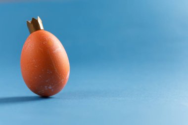 Mavi arka planda yumurta. Yakın plan plan. Taçlı bir kral suretinde bir yumurta. Uzayı kopyala Liderlik kavramı.