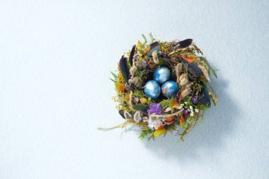 Paskalya 'da hayat. Soluk gri bir yüzeyde bir yuvada karışık renkli tavuk taşakları. Tatil konsepti. Uzayı kopyala Kartpostal tasarımı. Metnin altına yerleştir.