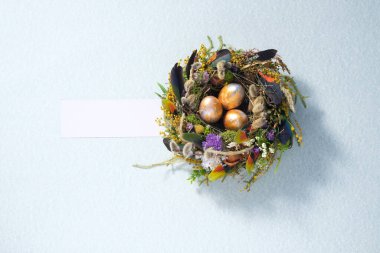 Paskalya 'da hayat. Soluk gri bir yüzeyde bir yuvada karışık renkli tavuk taşakları. Tatil konsepti. Uzayı kopyala Kartpostal tasarımı. Metnin altına yerleştir.