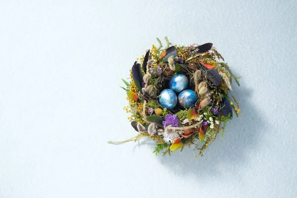 Easter still life. Mixed-colored chicken testes in a nest on a pale gray surface. Holiday concept. Copy space. Postcard design concept. Place under the text.