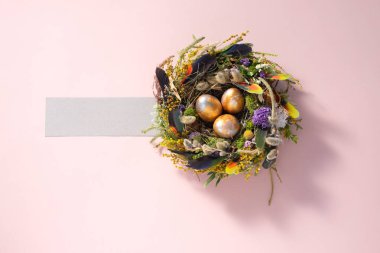 Paskalya 'da hayat. Soluk pembe bir yüzey üzerindeki bir yuvada karışık renkte tavuk taşakları. Tatil konsepti. Uzayı kopyala Kartpostal tasarımı. Metnin altına yerleştir.