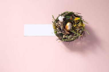Paskalya 'da hayat. Soluk pembe bir yüzeyde yuvadaki tavuk yumurtası. Tatil konsepti. Uzayı kopyala Kartpostal tasarımı. Metnin altına yerleştir.