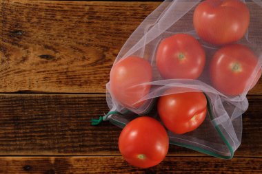 Sıfır atık, plastiksiz geri dönüşümlü, meyve domates veya sebze taşımak için üretilmiş poşet, ahşap bir yüzey. Tekrar kullanılabilir. Boşluğu kopyala.