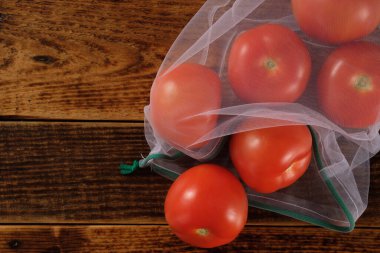 Sıfır atık, plastiksiz geri dönüşümlü, meyve domates veya sebze taşımak için üretilmiş poşet, ahşap bir yüzey. Tekrar kullanılabilir. Boşluğu kopyala.