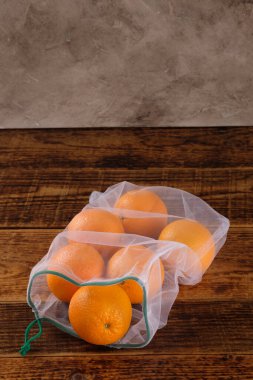 Sıfır atık, plastikten ücretsiz geri dönüşümlü meyve portakalı veya sebze taşımak için üretilen poşet, ahşap bir yüzey. Tekrar kullanılabilir. Boşluğu kopyala.