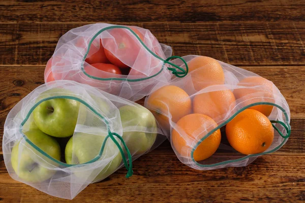 Zero waste, plastic free recycled textile produce bag for carrying fruit apple, orange, tomatos or vegetables, a wooden surface. Reusable using. Copy space.