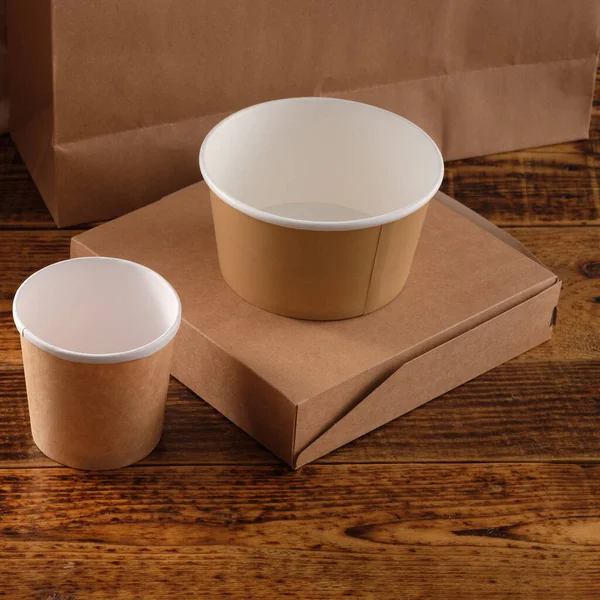 Street fast food paper cups, plates and containers. Eco-friendly food packaging on wooden background. Copy space. Carering of nature and recycling concept.