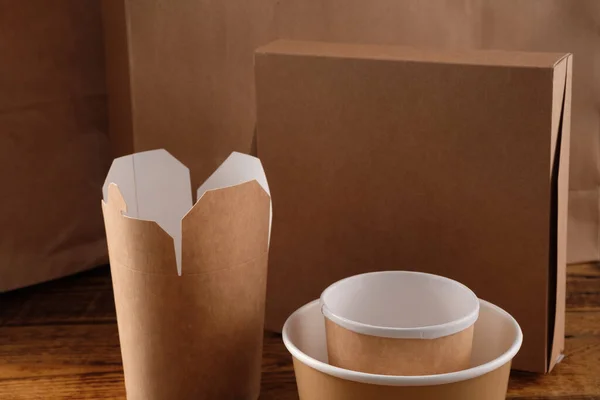 Street fast food paper cups, plates and containers. Eco-friendly food packaging on wooden background. Copy space. Carering of nature and recycling concept.