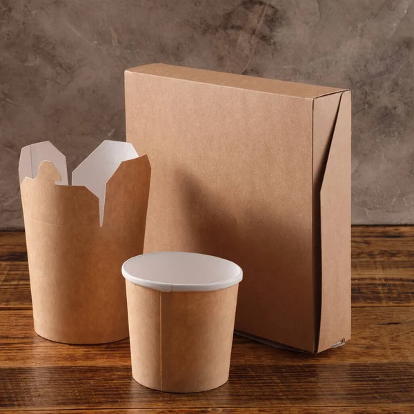 Street fast food paper cups, plates and containers. Eco-friendly food packaging on wooden background. Copy space. Carering of nature and recycling concept.