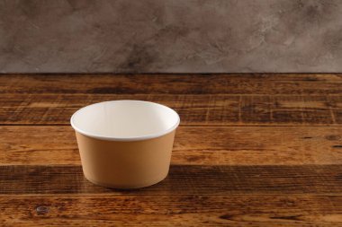 Tahta arka planda izole edilmiş büyük kahverengi kağıt tabak. Çevre dostu tek kullanımlık yiyecek ambalajı. Doğanın korunması ve geri dönüşüm kavramı. Boşluğu kopyala.