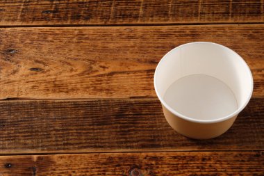 Tahta arka planda izole edilmiş büyük kahverengi kağıt tabak. Çevre dostu tek kullanımlık yiyecek ambalajı. Doğanın korunması ve geri dönüşüm kavramı. Boşluğu kopyala.