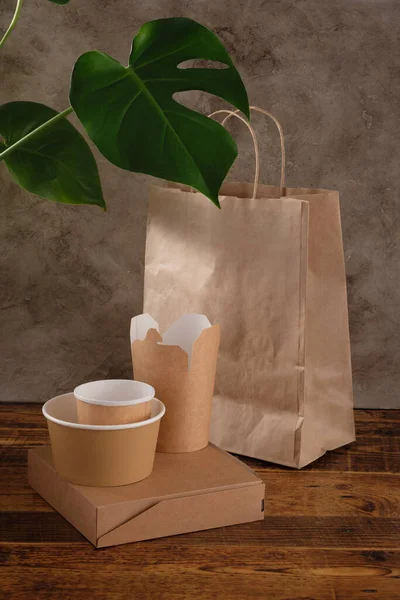 Street fast food paper cups, plates and containers. Eco-friendly food packaging on wooden background. Copy space. Carering of nature and recycling concept.